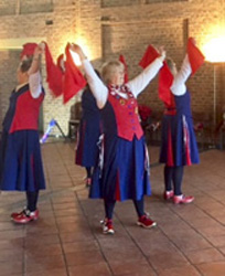 Nancy Butterfly dancers holding up bright red handkerchiefs during a dance at Avoncroft