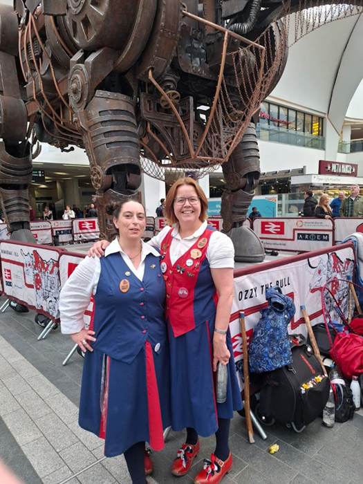 2 Nancy Butterfly Dancers standing in front of the Commonwealth Bull in 'Grand Central' Birmingham