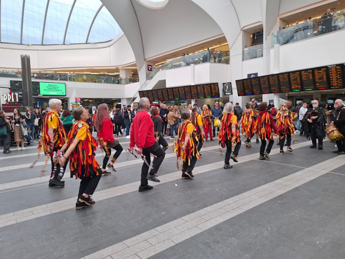 picture of a set of a dozen Black Adder Morris dancers dancing in their characteristic gold and black rag jackets