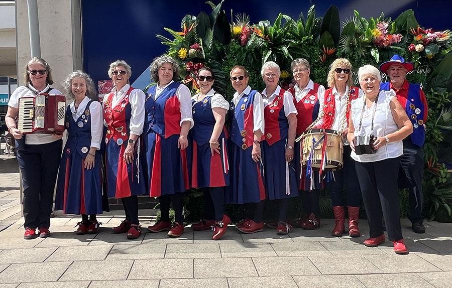 lineup of dancers and musicians in front of a striking floral display in Worcester