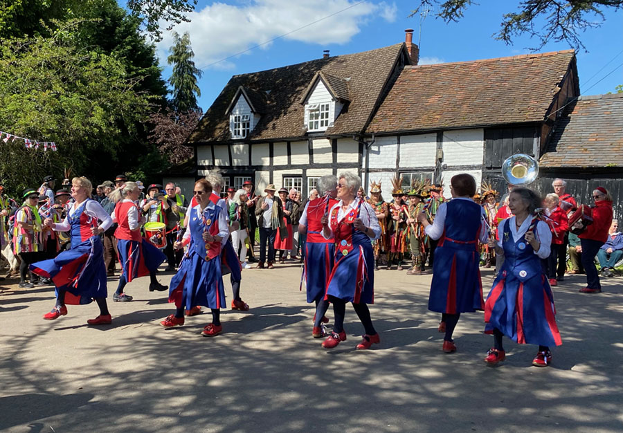 8 butterfly dancers in front of several watching morris sides and the band