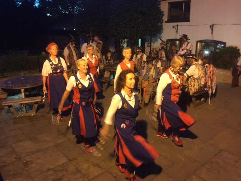 dancing outside the coach and horses inn. It is getting dark but illuminated by lights from the inn.