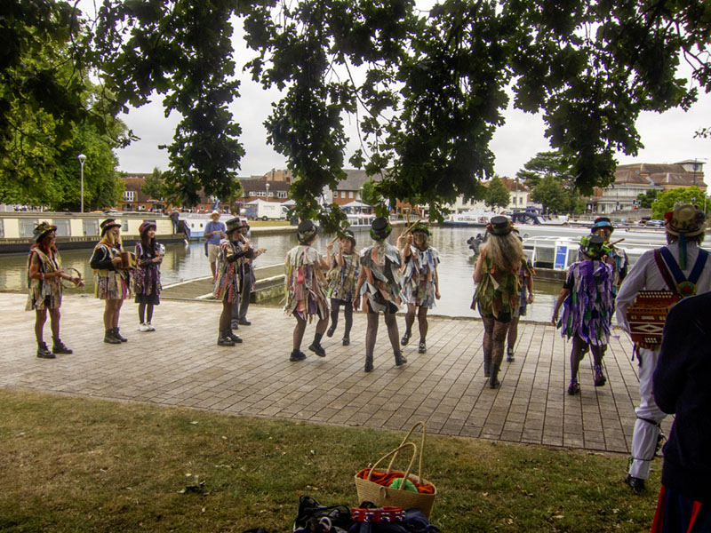 Ledbury Morris dressed in their Border Morris Tatters, dancing on the pathway alongside the canal basin in the background