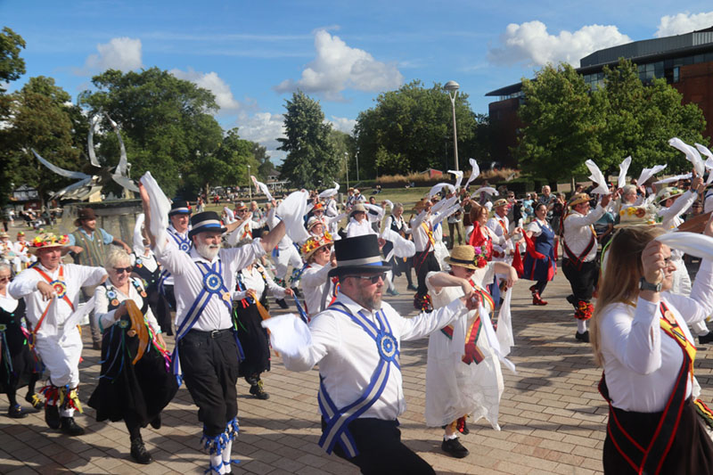 dozens of Morris dancers mainly in cotswold costume, dancing in the final mass dance