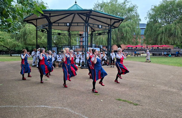 set of 8 dancers in front of the bandstand in the green and wooded recreation ground