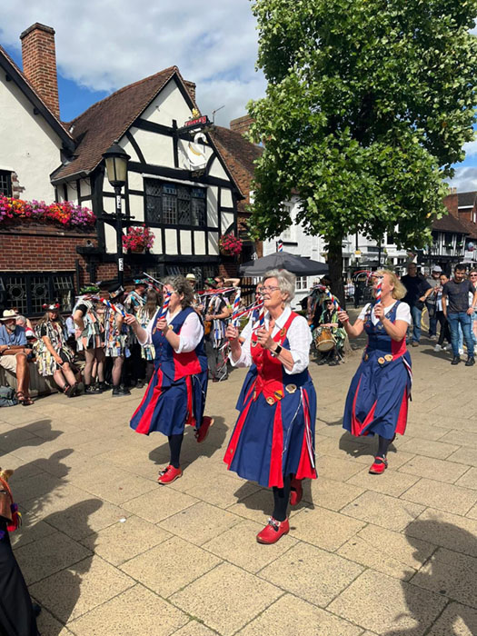 4 sunlit dancers on the pavement in front of the White Swan Hotel