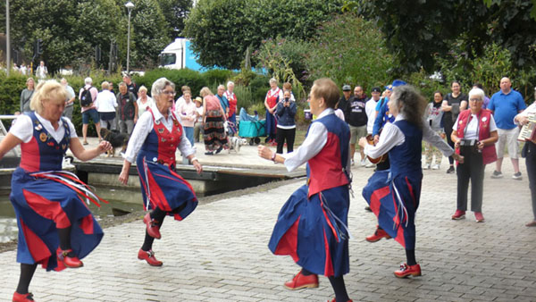 4 dancers at the edge of the canal basin with a number of passers by stopping to watch