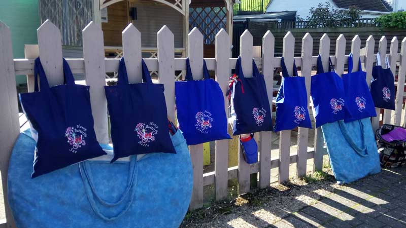 line of bags with nancy butterfly decoration hanging from a picket fence in Upton