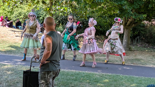 4 Belly dancers in their elaborate costumes dancing on a path in the park