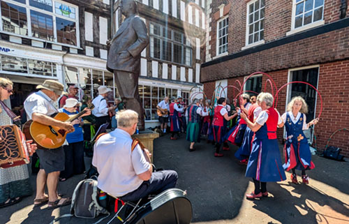 View of Butterfly dancers and musicians on either side of the Stanley Baldwin Statue of him standing on a plinth